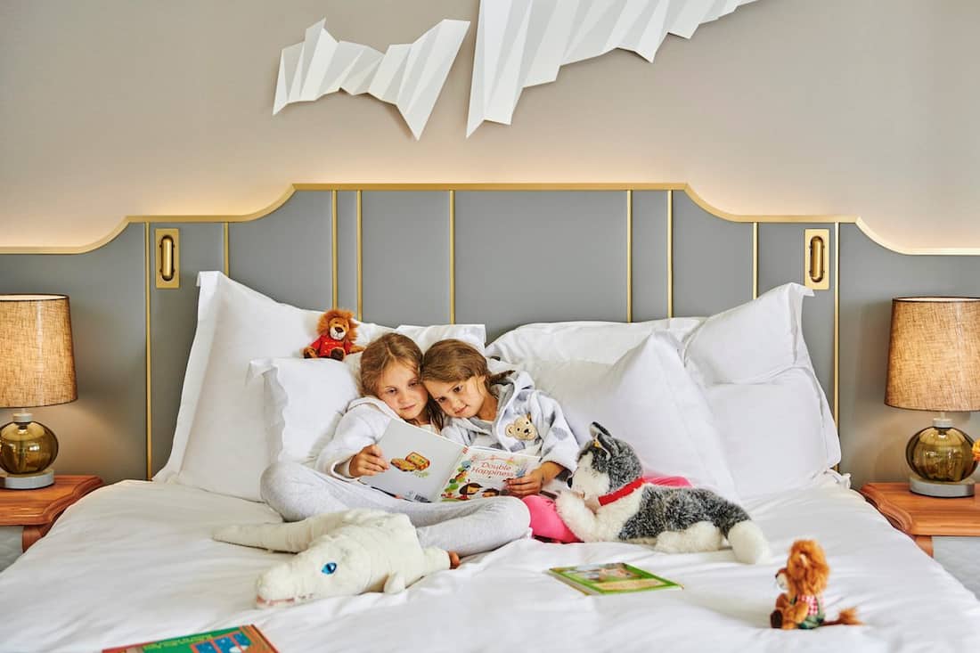 younger fans reading in bed with stuffed animals